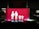 A bright red sign features white pictograms representing a family, consisting of two adults on the left and two children on the right, all holding hands. The scene is set against a dark background, suggesting it might be located in a parking area or similar environment.