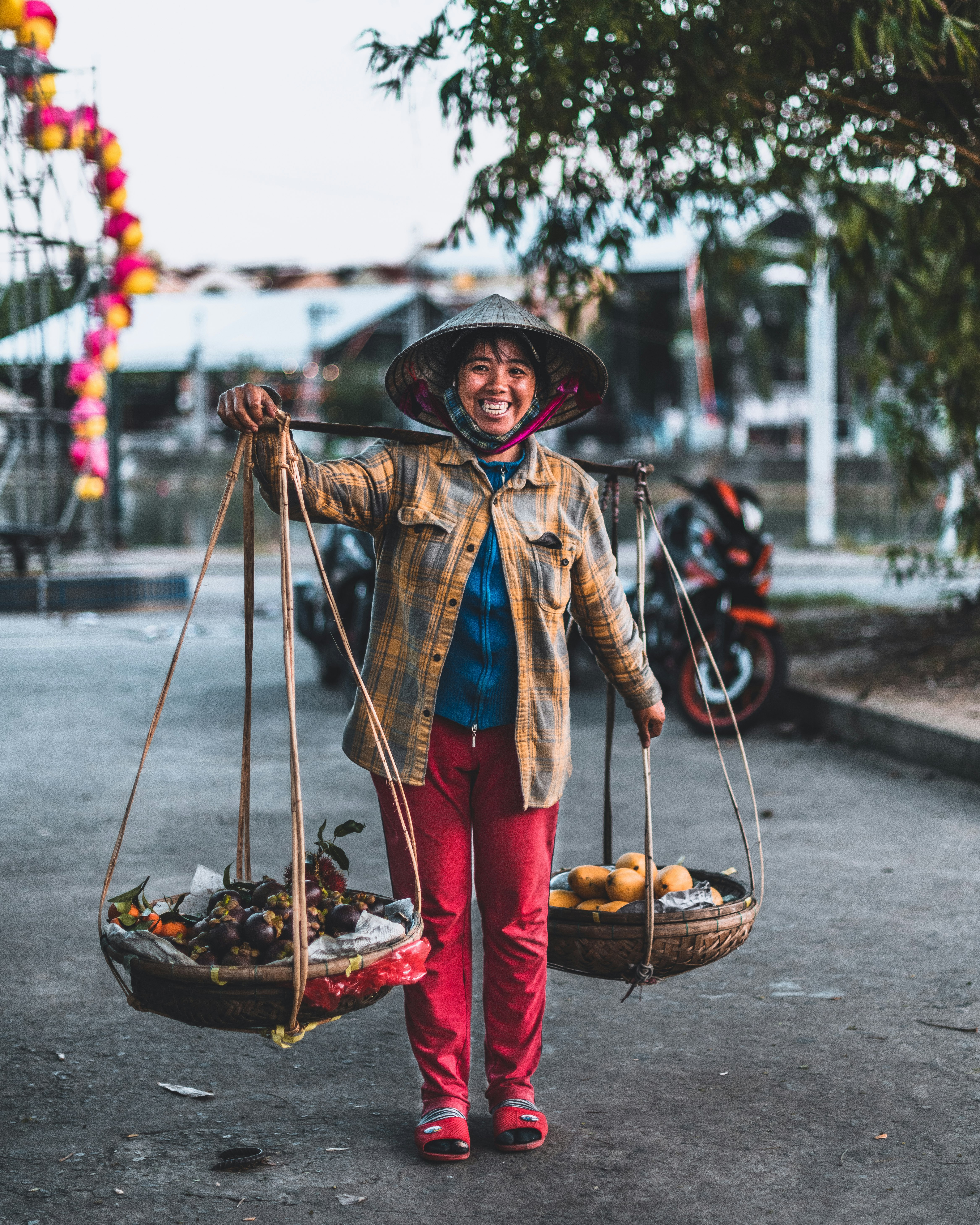 woman in blue and brown coat wearing red hat carrying brown basket with fruits