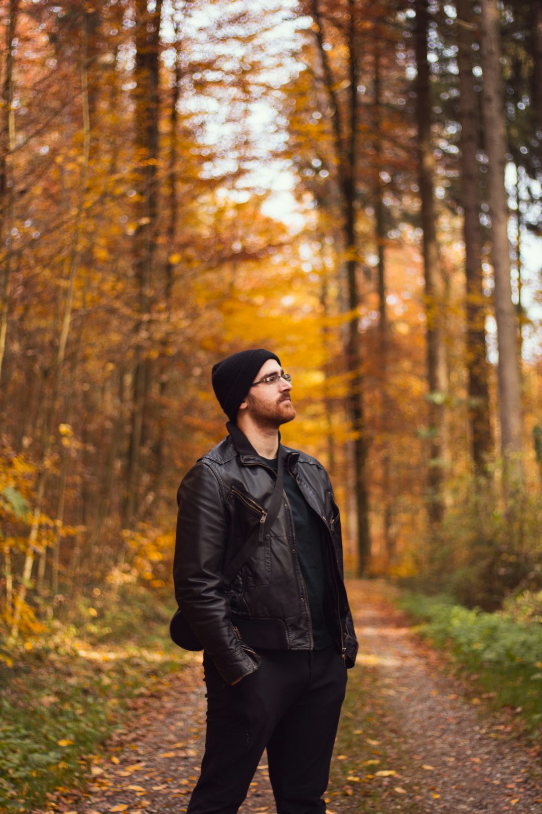 man in black jacket and black knit cap standing in forest during daytime