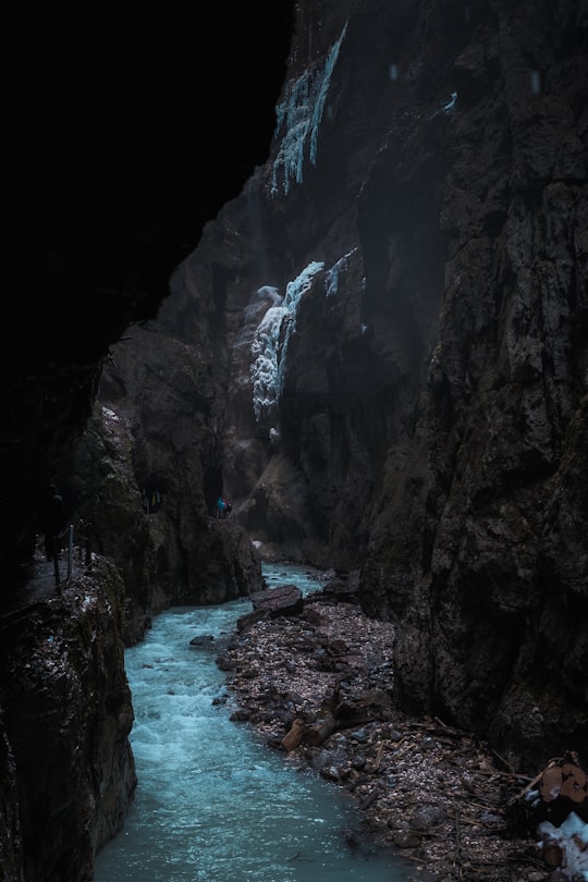 body of water between rocky mountains during daytime in Partnachklamm Germany