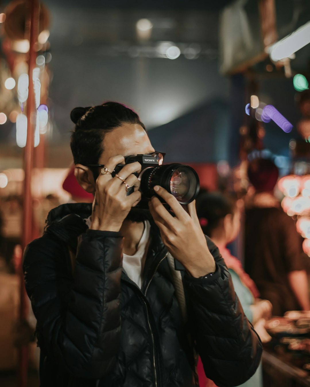 man in black leather jacket holding black dslr camera