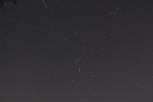 A clear night sky filled with numerous stars scattered across the dark background, exhibiting a cosmic view. Some star patterns may resemble well-known constellations.