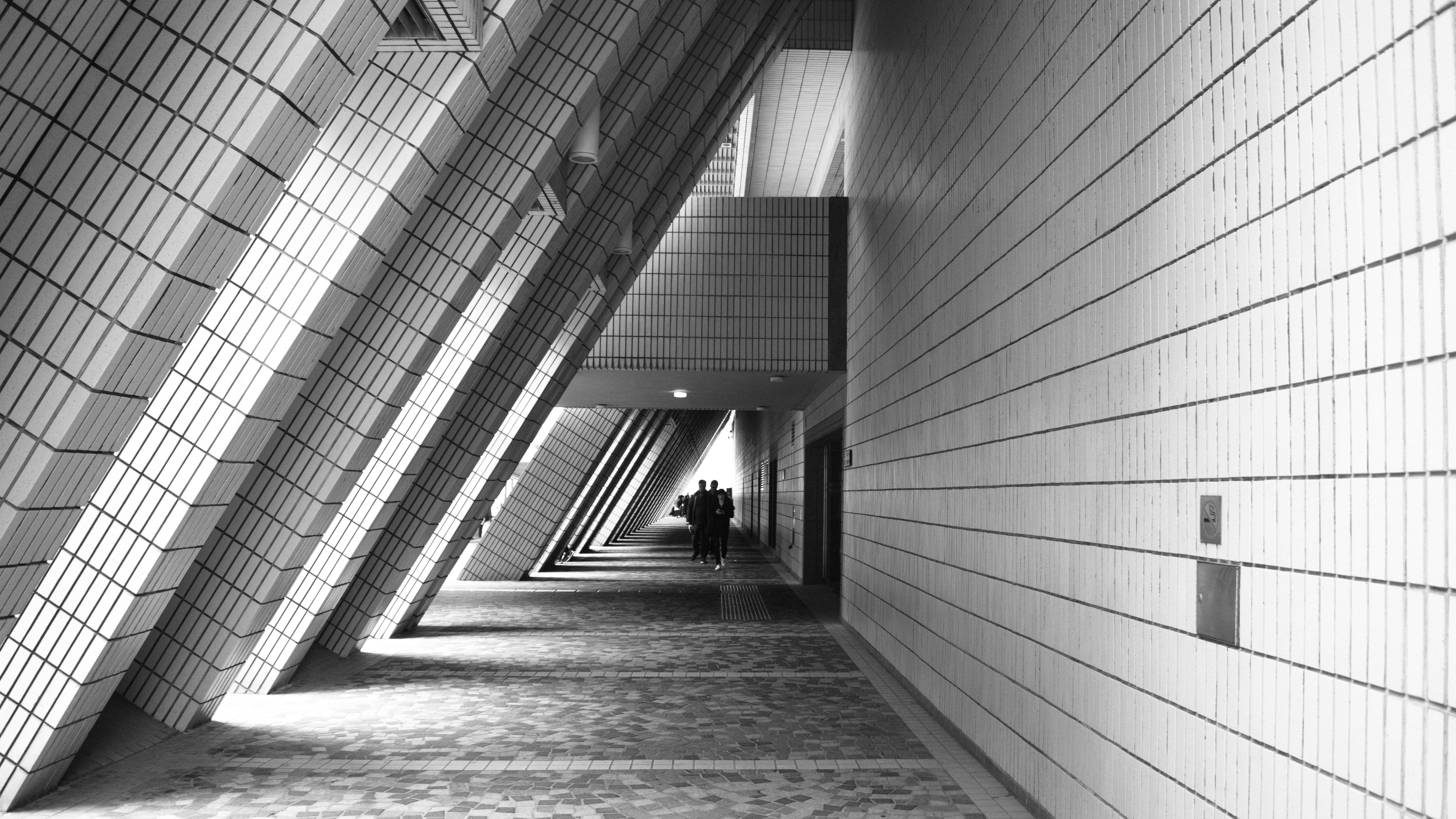 grayscale photo of person walking on hallway