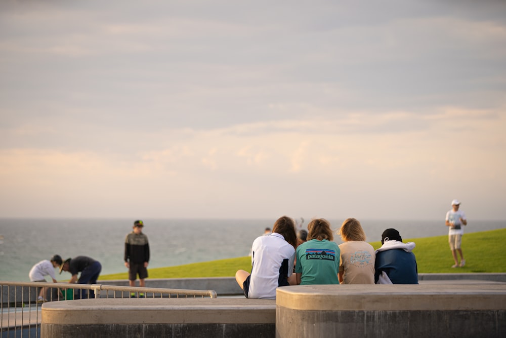 a group of people sitting on a bench near the ocean