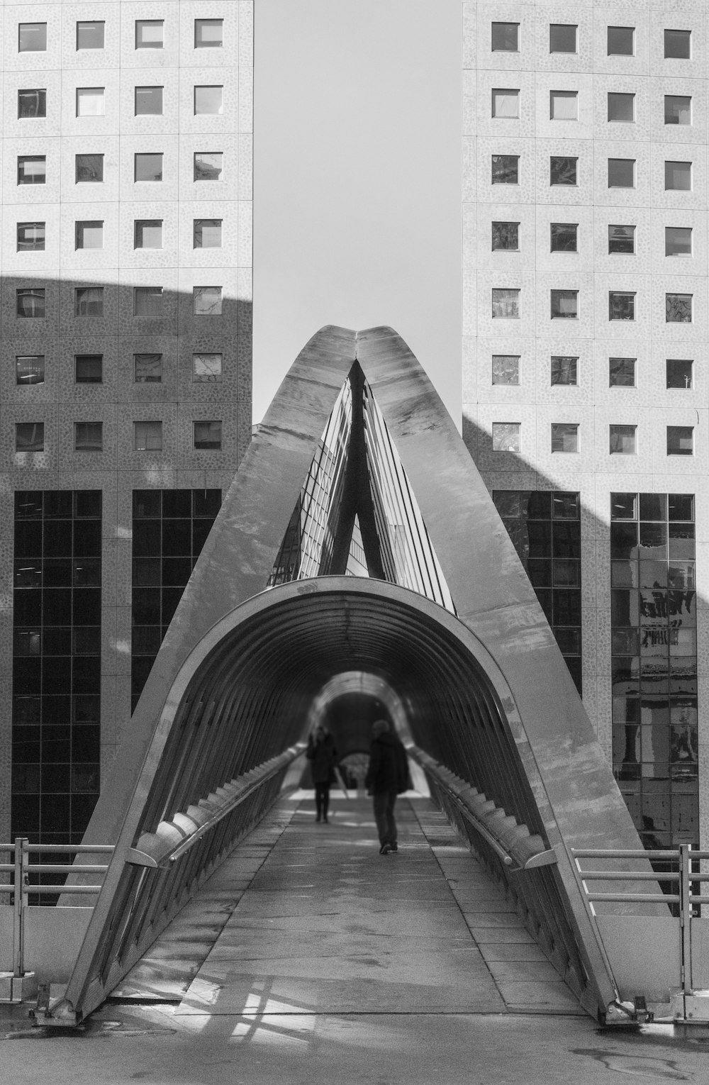 grayscale photo of man walking on bridge