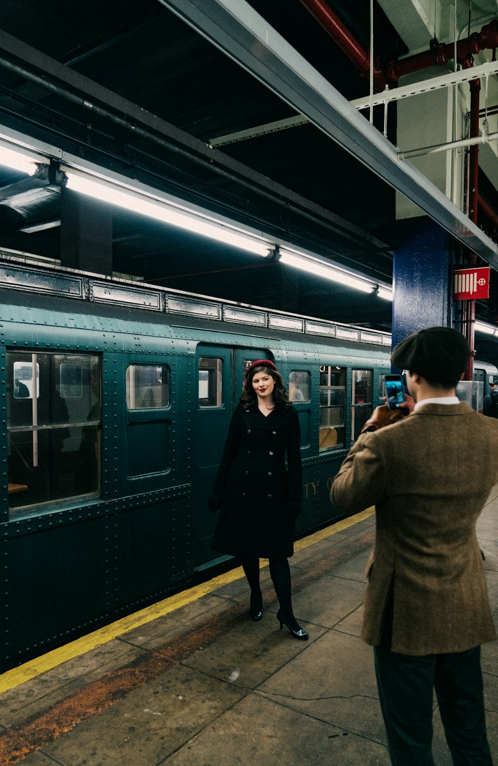 man in brown coat standing near train