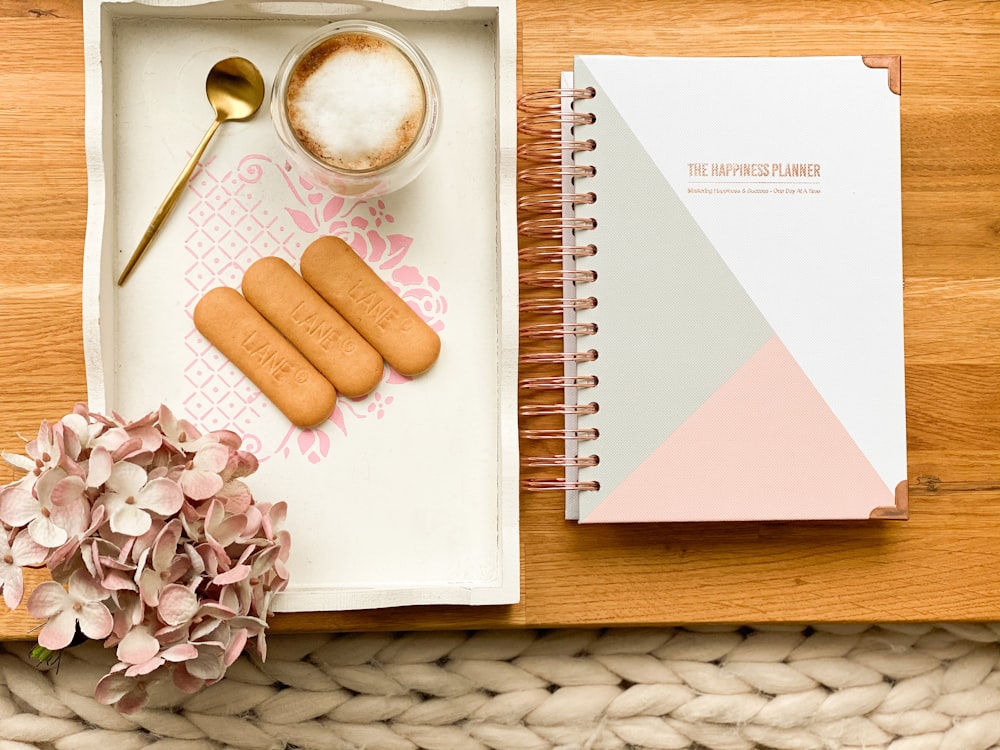 white printer paper beside stainless steel spoon and white ceramic mug on brown wooden table