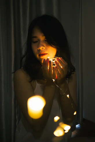 woman in black tank top holding lighted candle