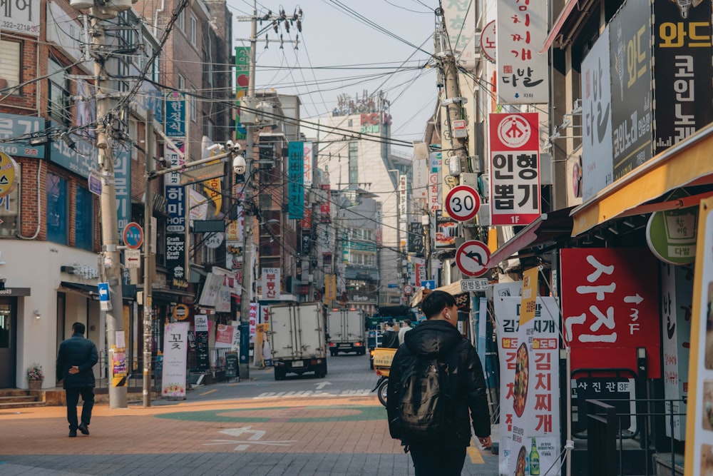 man in black jacket walking on sidewalk during daytime