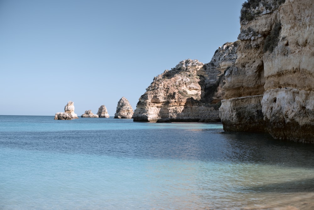 Formación rocosa marrón en el mar azul bajo el cielo azul durante el día