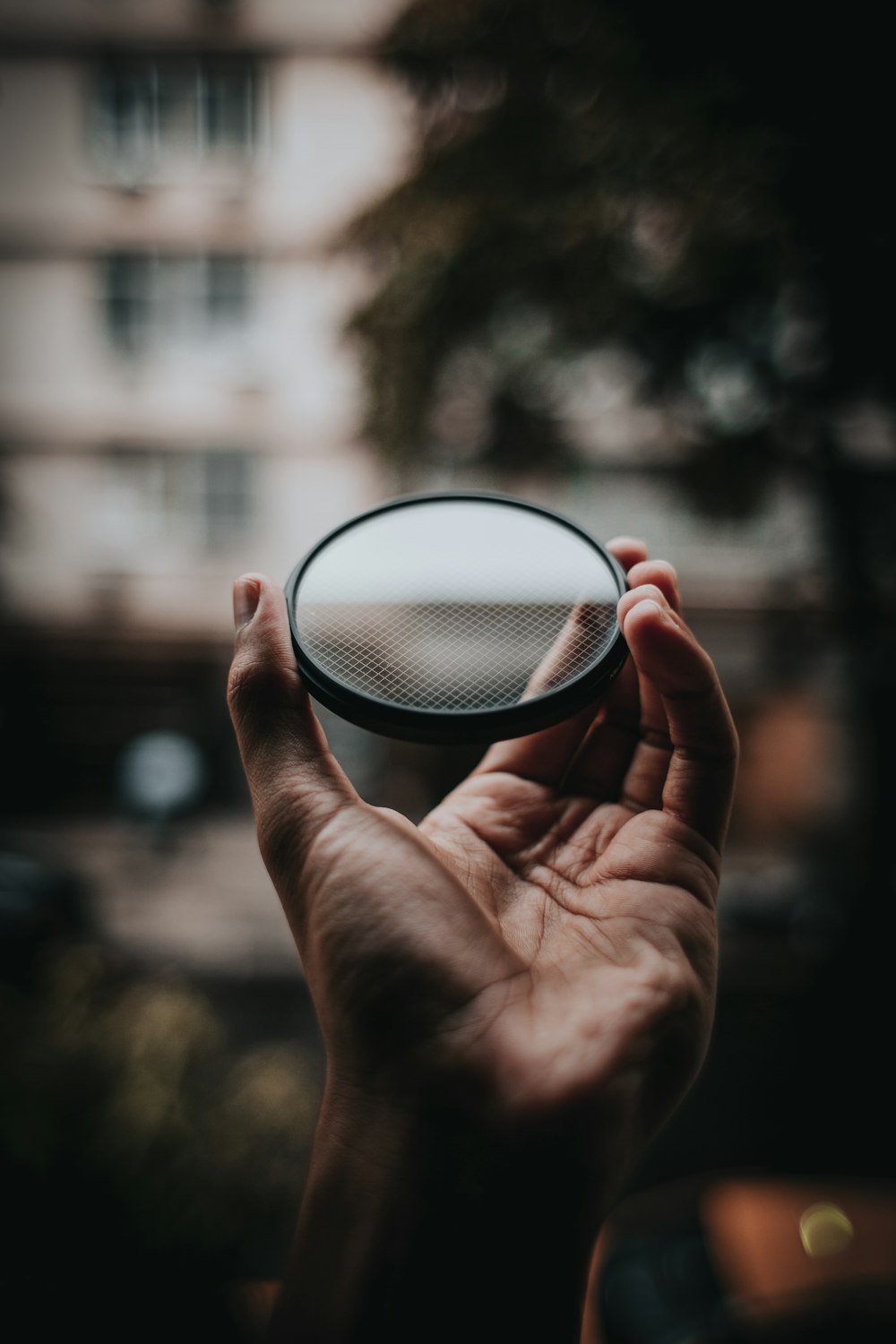 person holding round mirror with light