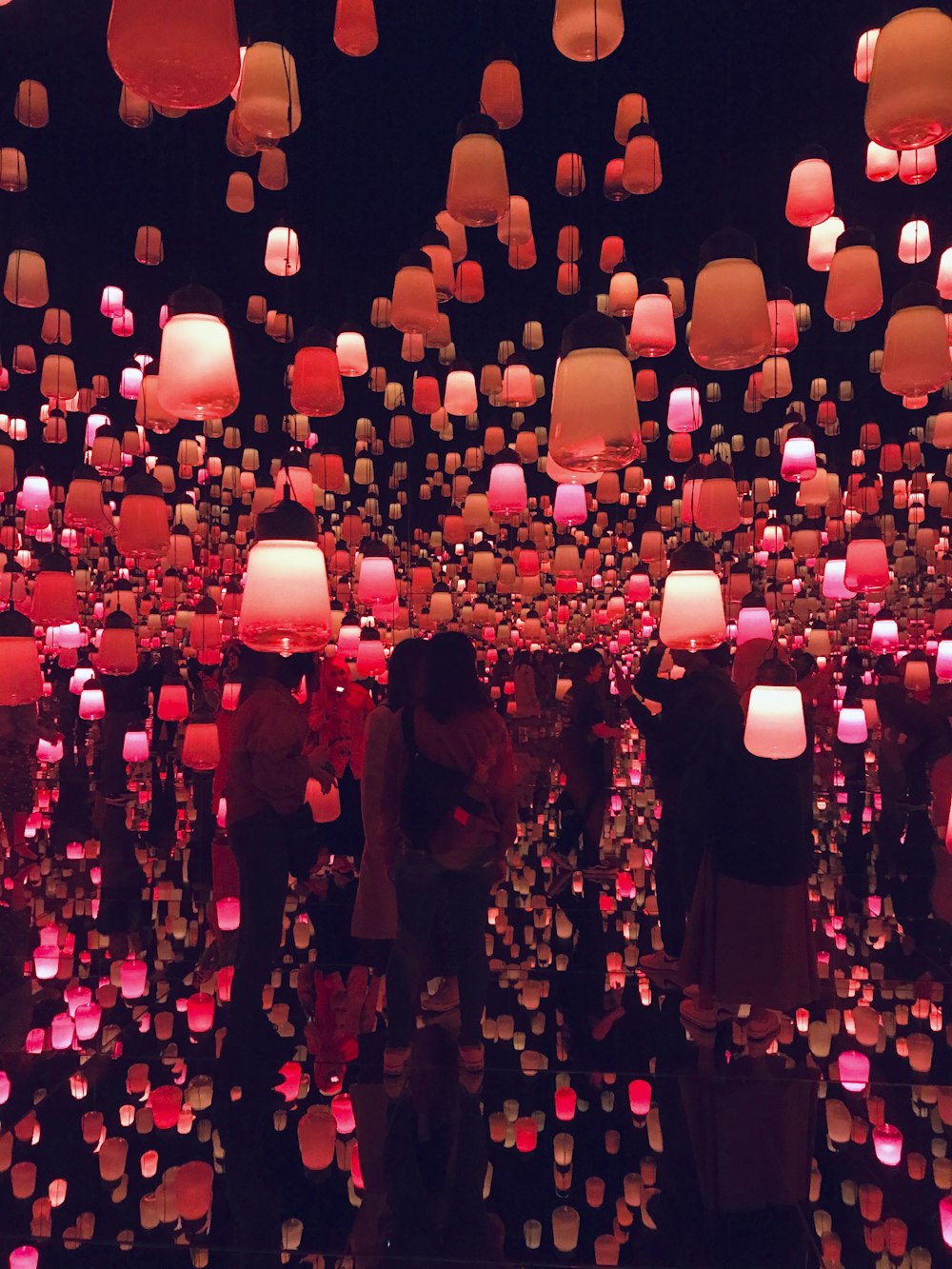 people standing under lighted pendant lamps