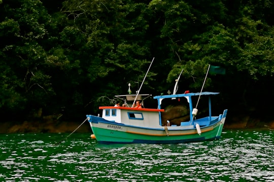 blue and white boat on body of water during daytime in Ilhabela Brasil