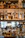 Multiple bottles of whiskey and spirits are displayed on a wooden shelf with warm lighting that highlights the labels. The scene appears to be in a bar setting with a luxurious and sophisticated atmosphere. The background shows a blurred view of people seated, adding to the ambience.