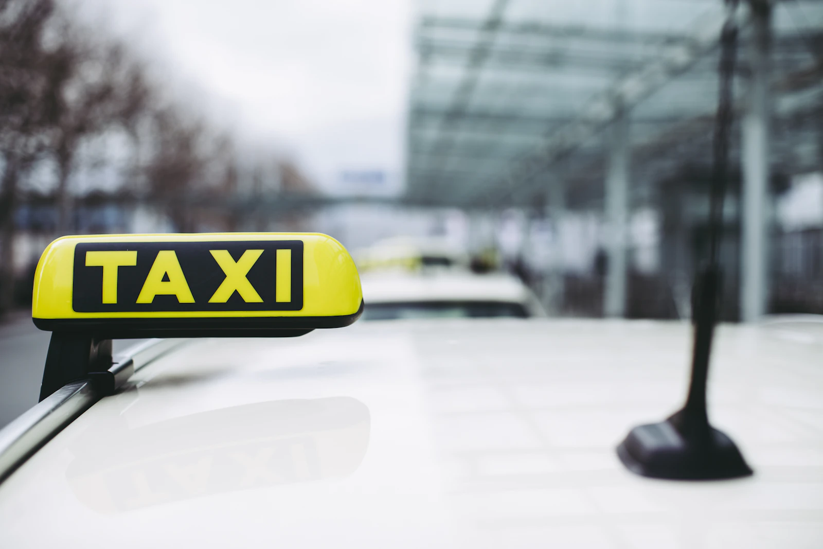 A yellow and black taxi sign above an airport pickup lane.