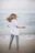 woman in white shirt and blue denim jeans standing on beach shore during daytime