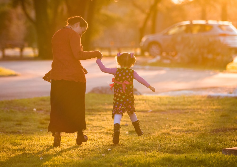 man and woman holding hands while walking on green grass field during daytime