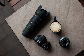 A flat lay of lifestyle gear including a camera, fitness tracker, and coffee beans on a textured fabric.