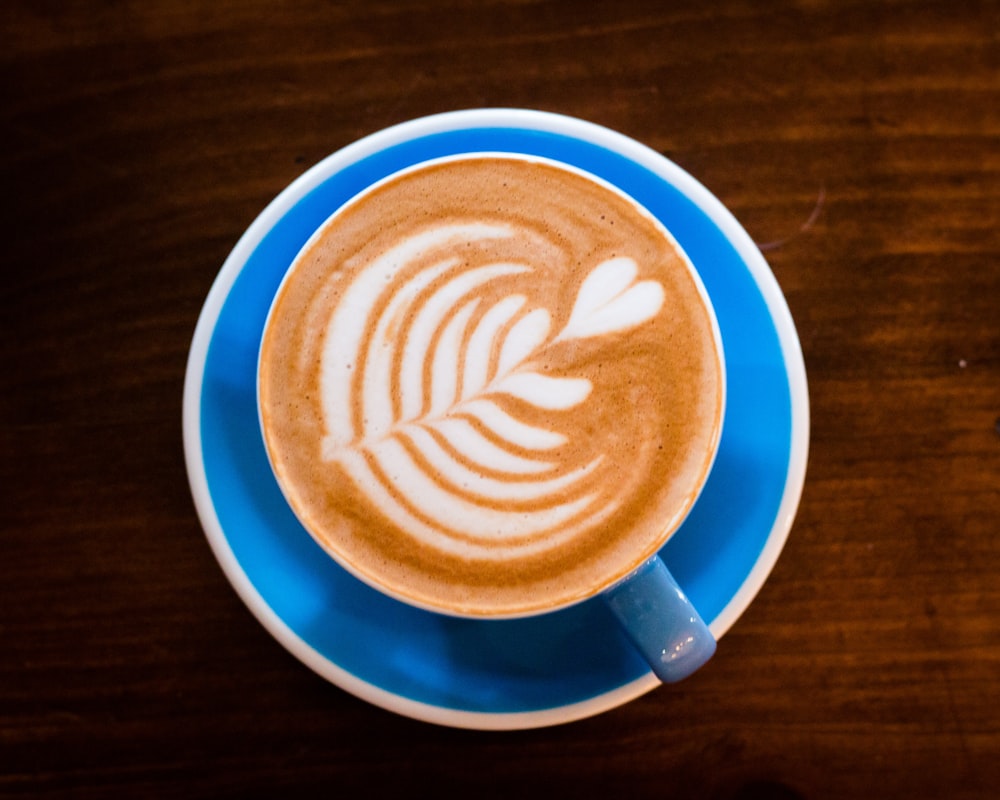 white and blue ceramic mug with cappuccino