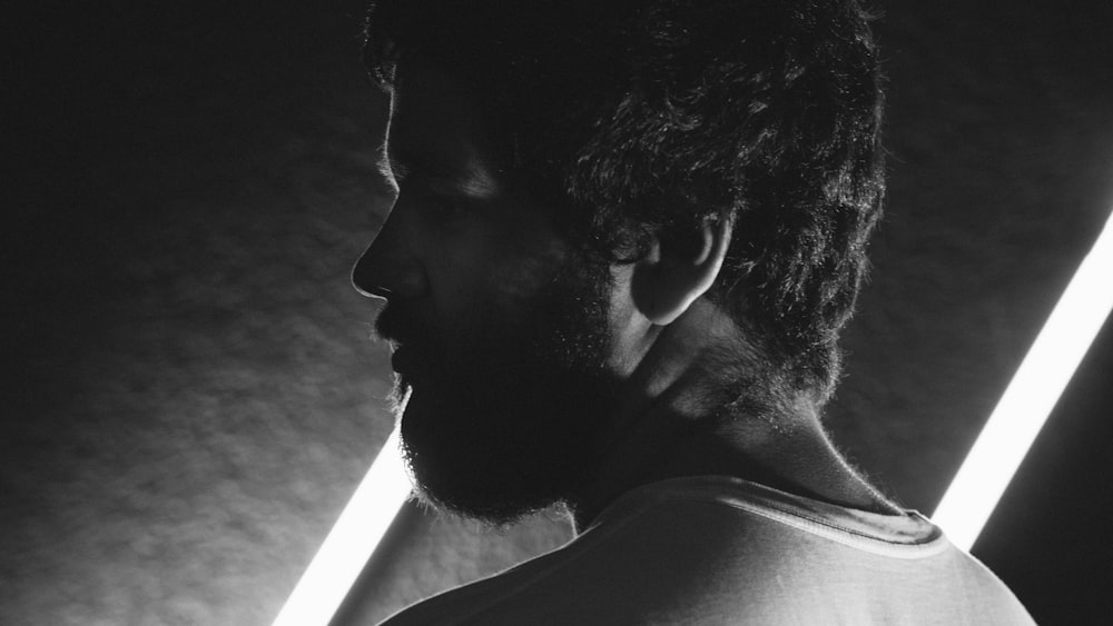 Un homme aux cheveux longs et à la barbe sur une photo en noir et blanc