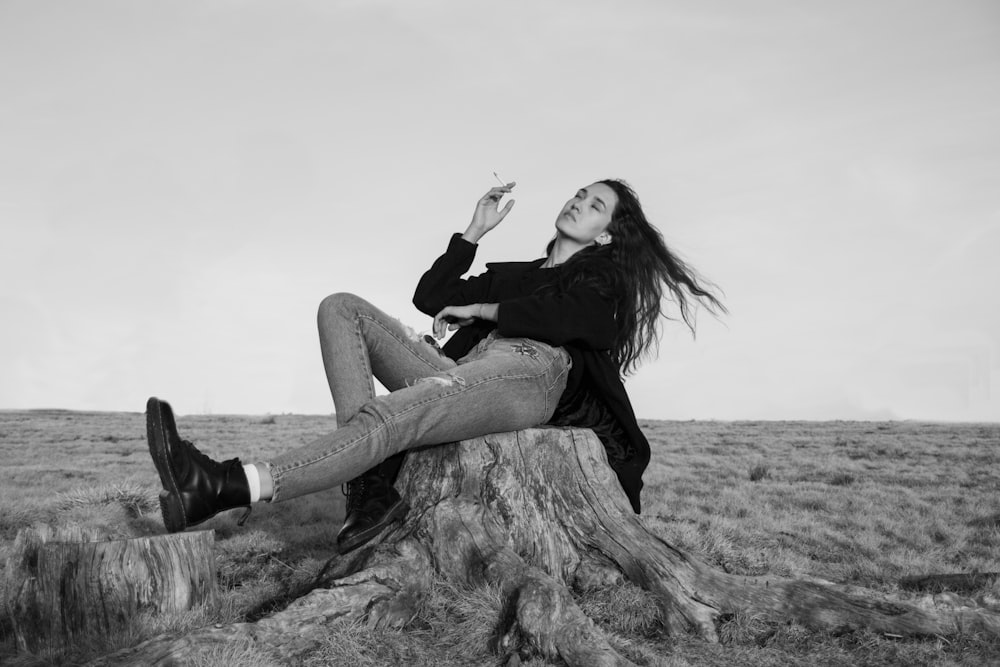 Femme en chemise noire à manches longues et jean en denim bleu assise sur un rocher