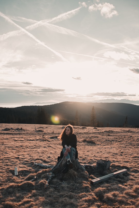 woman in blue denim jacket sitting on brown rock during daytime in Rogla Slovenia