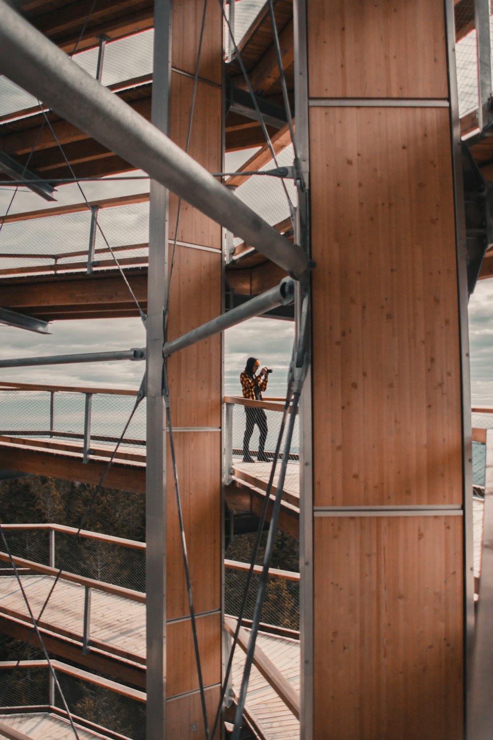 woman in black tank top and black pants standing on brown wooden ladder during daytime