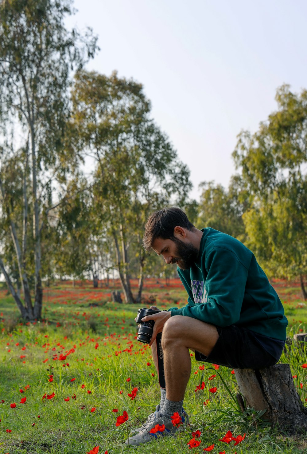 uomo in camicia viola che si siede sul campo di erba verde durante il giorno
