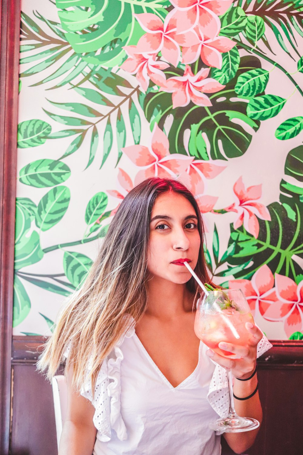 woman in white shirt drinking from clear drinking glass