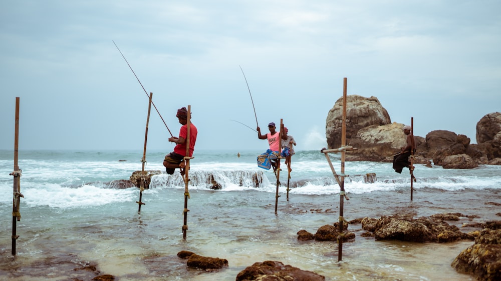 3 men fishing on sea during daytime