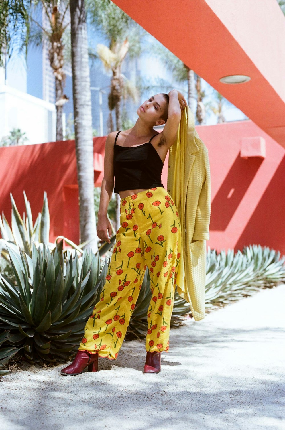 woman in black tank top and yellow pants standing beside green plant during daytime