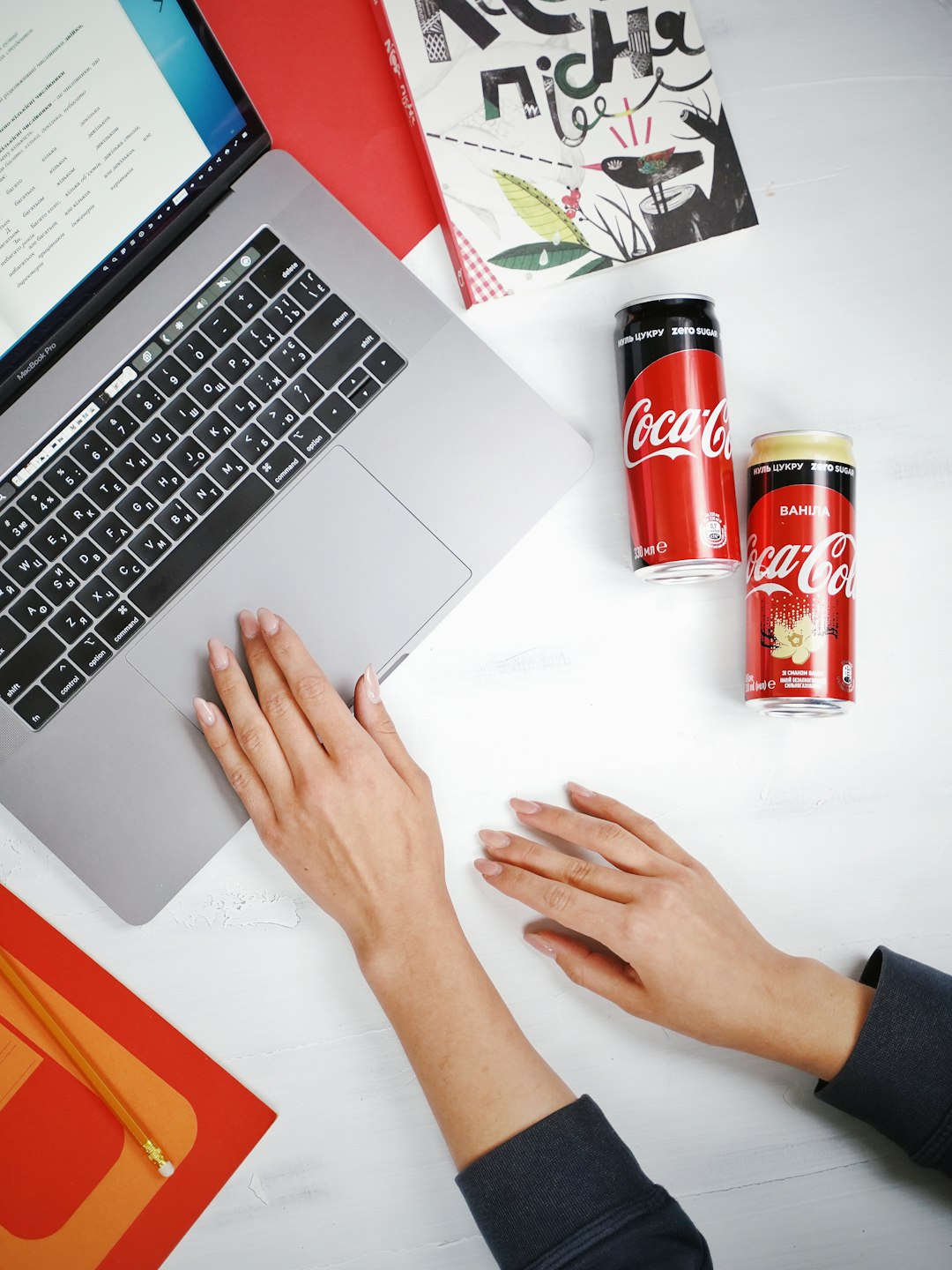 person using macbook pro beside coca cola can