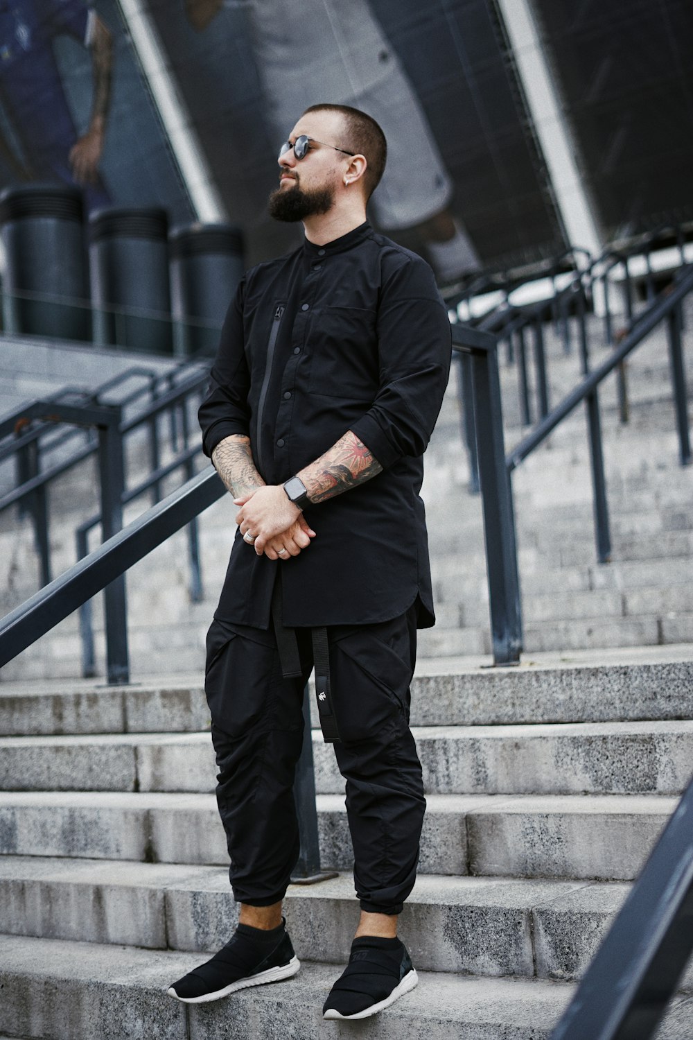 man in black dress shirt and black pants standing on gray concrete stairs