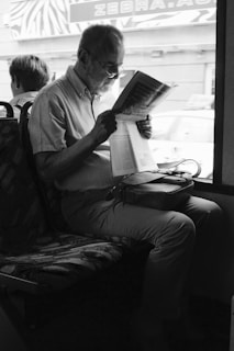 man reading book sitting on chair