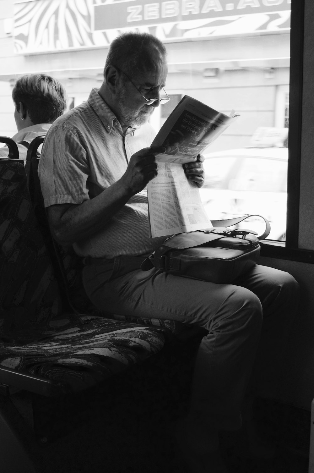 man reading book sitting on chair
