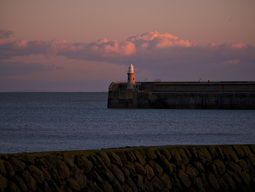 white lighthouse near body of water during sunset