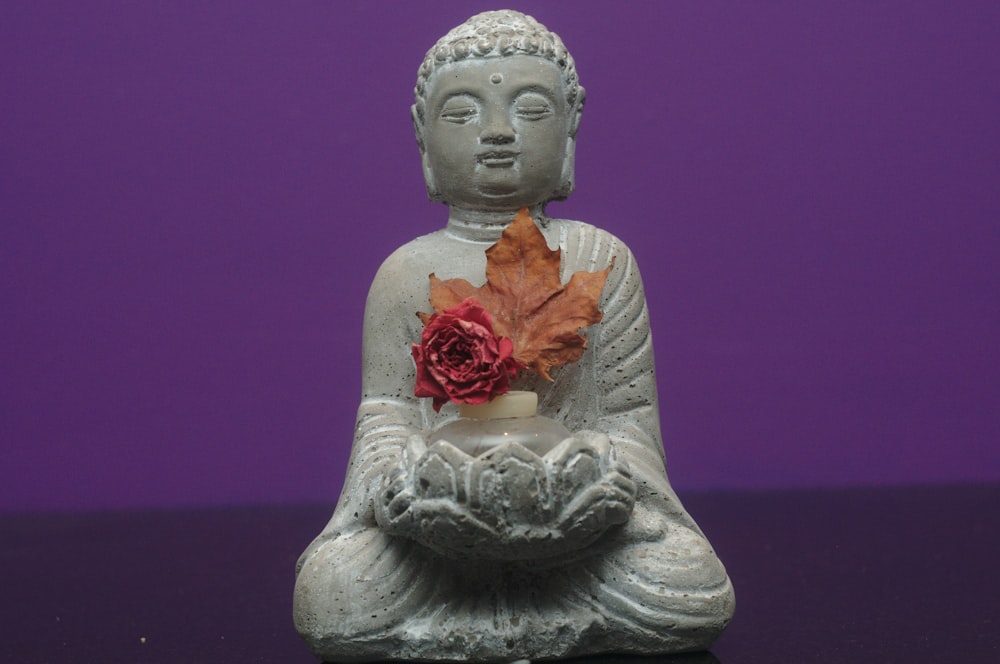 white ceramic buddha figurine with red rose