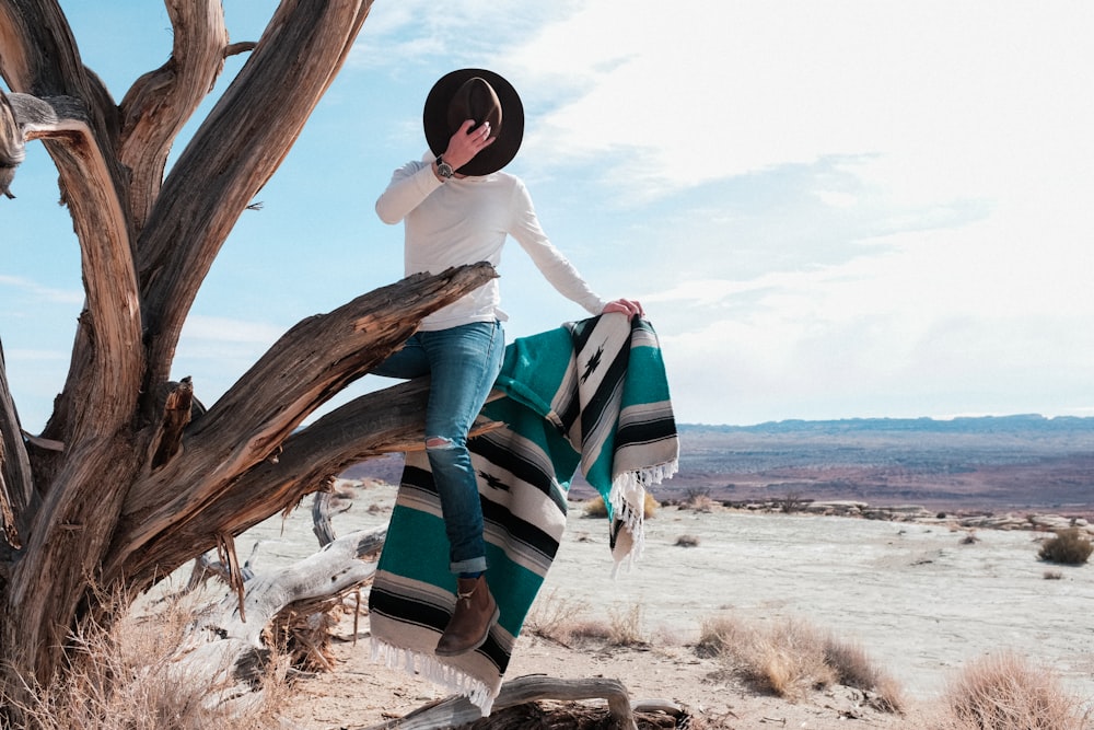 woman in white long sleeve shirt sitting on brown wood log during daytime