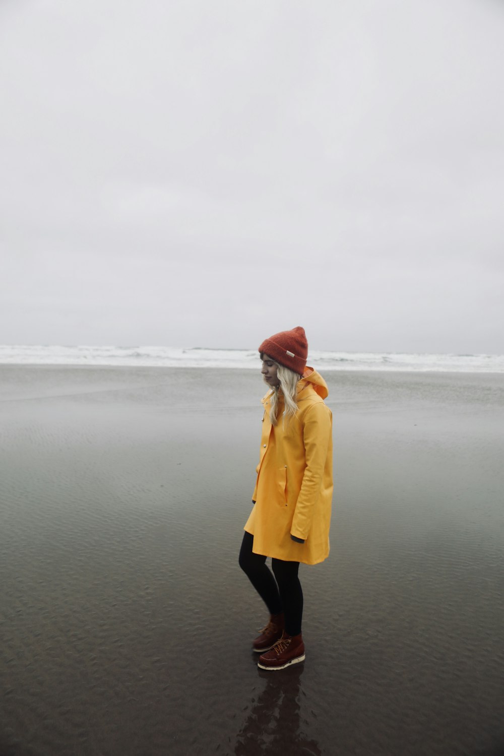 woman in yellow coat standing on seashore during daytime