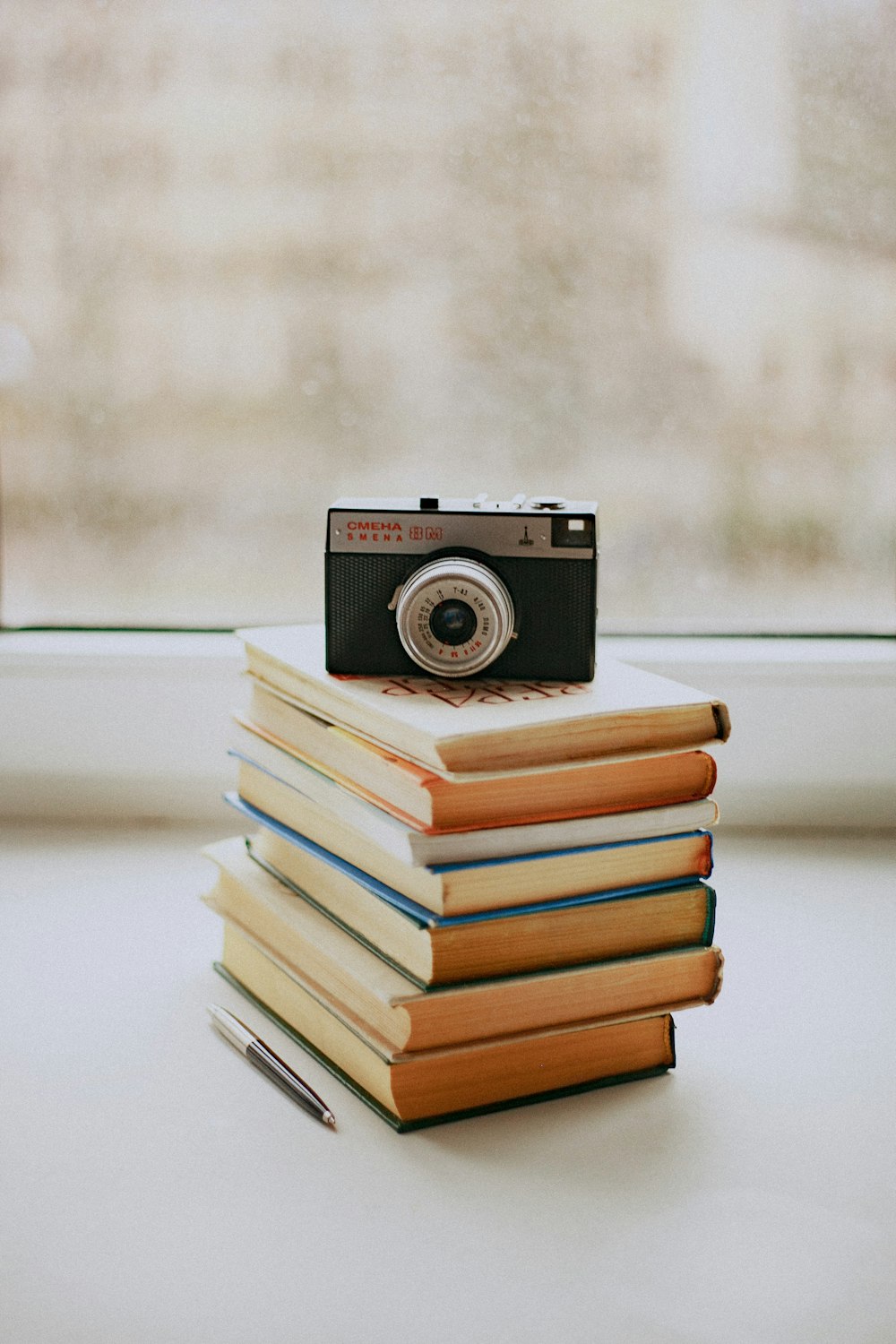 black and silver camera on stack of books