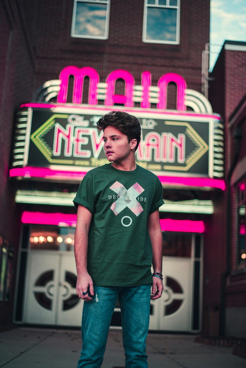 man in black crew neck t-shirt standing near red and purple neon signage