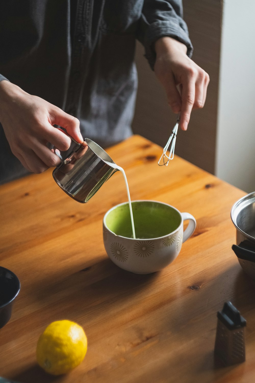 person pouring green liquid on white ceramic cup