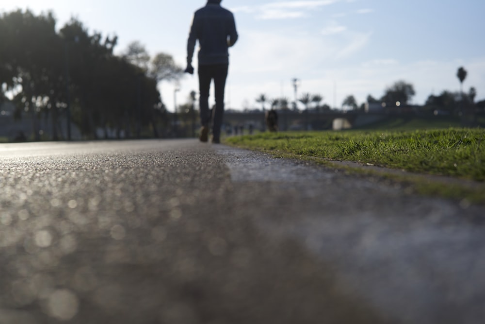 person in black jacket and pants walking on gray concrete road during daytime