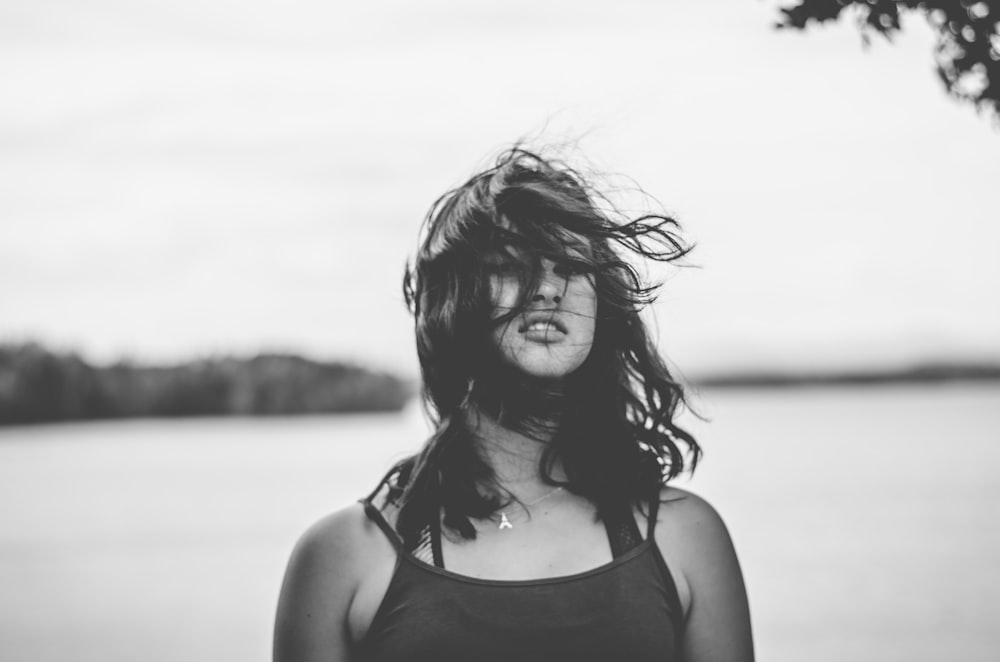 woman in tank top standing near body of water