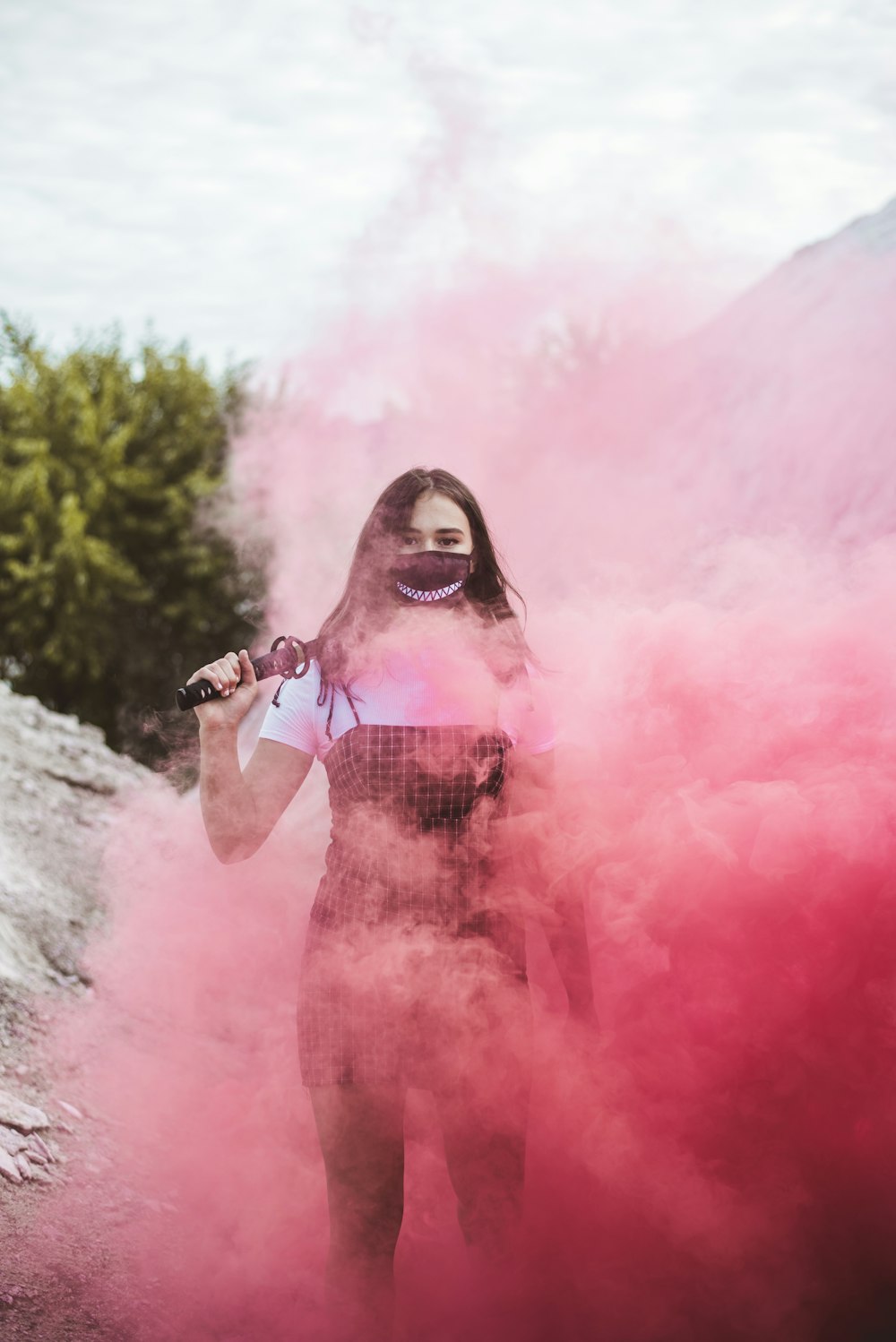 Femme en robe fleurie rouge et blanche debout sur la fumée rose