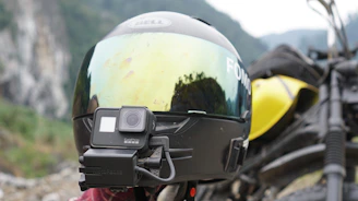 Close-up of a camera mounted on a bike helmet filming a scenic mountain ride.