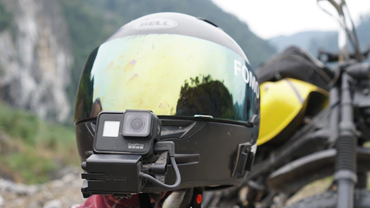 Close-up of a camera mounted on a bike helmet filming a scenic mountain ride.