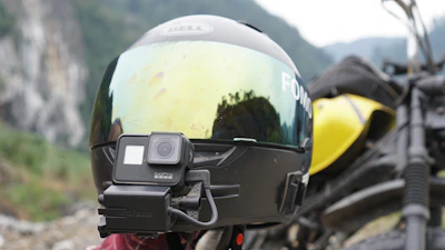 An action camera mounted on a helmet, capturing an adventurous mountain biking scene.