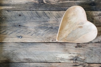 A rustic wooden bowl with smooth curves resting on a textured fabric.
