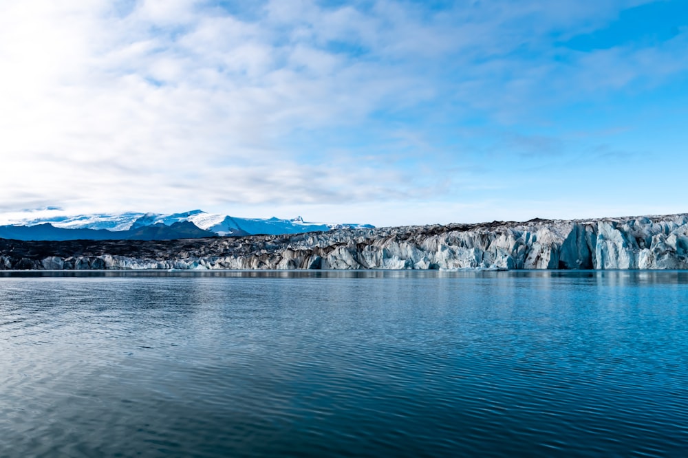 body of water near mountain under blue sky during daytime